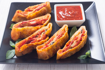 Pizza roll stromboli with cheese salami olives and tomatoes