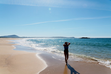 Frau allein am Strand im Gegenlicht