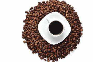 white cup of coffee on a white saucer stands on a hill of coffee beans on a white background isolate top view