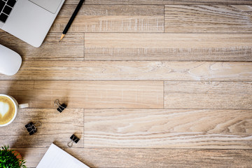 The office desk flat lay view with laptop, mouse, tree, black clip, heart latte coffee cup, notebook, pencil on wood texture background.