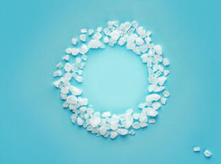 round frame of scattered sea salt on a color background
