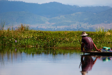 Fototapeta na wymiar Mirroring traditional fisherman with hat on his boat on Lake Inle, Myanmar/Birma.