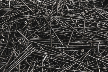 Pile of metal tapping chrome screws abstract background. Iron or metal screw nails stack industrial construction industry background. 