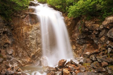 Waterfall outside of skagway alaska, with pine trees and jagged rocks