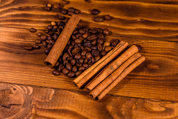 Pile of the coffee beans and cinnamon sticks on wooden table