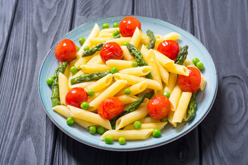Penne pasta salad with asparagus , tomatoes and peas