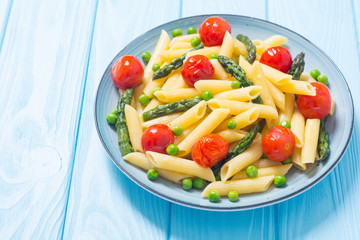 Penne pasta salad with asparagus , tomatoes and peas