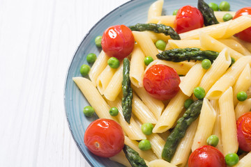 Penne pasta salad with asparagus , tomatoes and peas