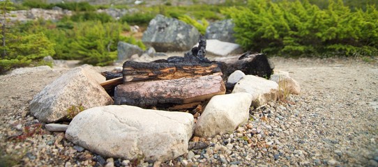 Close up on wood campfire surrounded by rocks in Canada