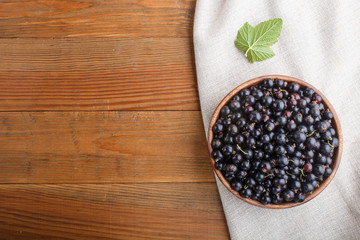 Fresh black currant in wooden bowl on wooden background. top view.