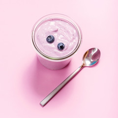 Yogurt with berries, blueberry, yogurt on pink copy space background, square image