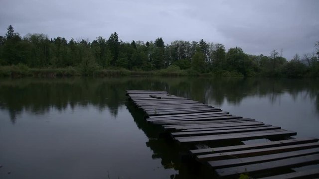 Rain falls on an old partially ruined wooden pier