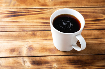 Black coffe in white cup on wooden background