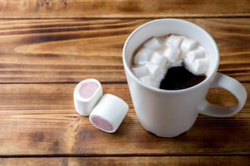 Cup of coffee with marshmallows on wooden table