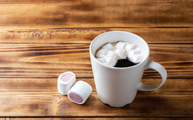 Marshmallow and cup with black coffe on wooden background