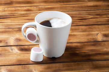 Cup of coffee with marshmallows on wooden table