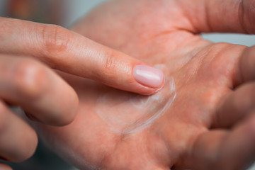 Fingers apply cream to skin. Close up