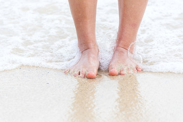 Fototapeta na wymiar Woman bare foot walking on the summer beach. close up leg of young woman walking along wave of sea water and sand on the beach. Enjoyment barefoot walk outdoor with freedom. Relaxation Travel Concept.