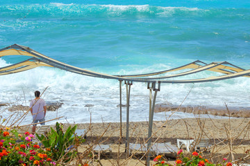 Boy stands on the beach and looks at the sea.
