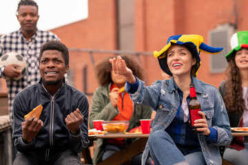 Tense young sports fans with snack and beer watching football broadcast