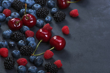 Naklejka na ściany i meble Blackberries,blueberries,raspberries,cherries on black concrete background. Healthy food
