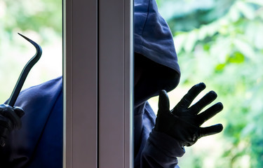 A burglar tries to break into a house in bright daylight. Concept crime.