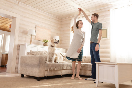 Happy Married Couple A Charming Girl And Tall Man Are Dancing Their New Living Room Of Their Small Country House Recently Bought Along With Their Beloved Dog