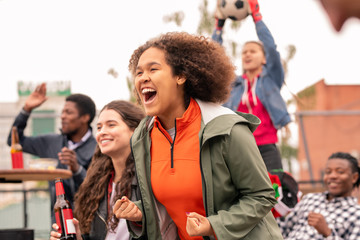 Ecstatic intercultural friends cheering for their football team after goal