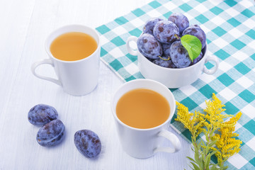 Plums in the bow fresh plums juice on a white wood background, rustic style