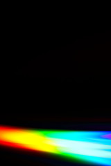 Beams of light refracting and creating a rainbow spectrum of colours against a black background