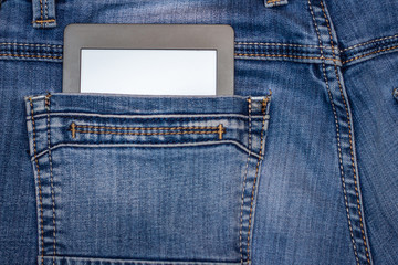An e-reader hidden in a pocket of jeans pants. Close-up with selective focus. Copy space. Training and technology concept