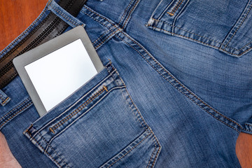 An e-reader hidden in a pocket of jeans pants. Close-up with selective focus. Copy space. Training and technology concept