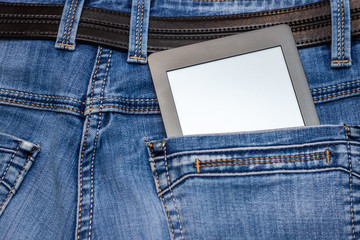 An e-reader hidden in a pocket of jeans pants. Close-up with selective focus. Copy space. Training and technology concept