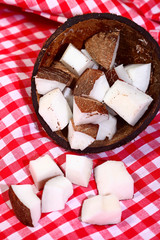Coconut cut in half and diced on a red and white tablecloth