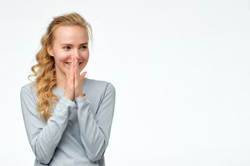 Happy cheerful young woman rejoicing at positive news or birthday gift, looking aside with joyful and charming smile.