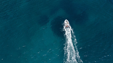 Aerial bird's eye view of inflatable rib boat cruising in high speed in turquoise clear water sea