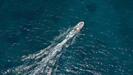 Aerial bird's eye view of inflatable rib boat cruising in high speed in turquoise clear water sea