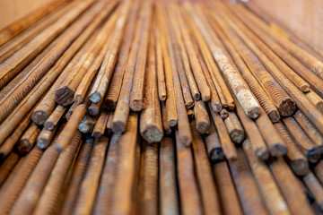 Close up selected focus view stack of straight old rusty high yield stress deformed reinforcement steel or iron bars. Background horizontal random pattern of deformed iron bars. 
