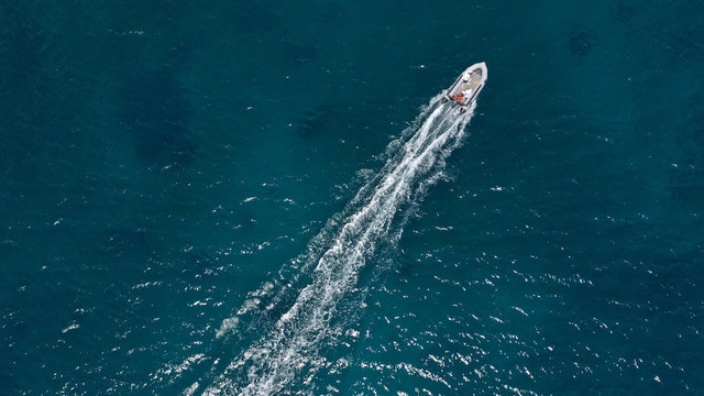 Aerial bird's eye view of inflatable rib boat cruising in high speed in turquoise clear water sea