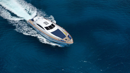Aerial drone tracking photo of luxury yacht with wooden deck cruising in deep blue waters of...