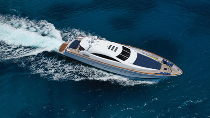 Aerial drone tracking photo of luxury yacht with wooden deck cruising in deep blue waters of...