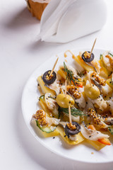 Salted herring on skewers with cheese and olives on plate