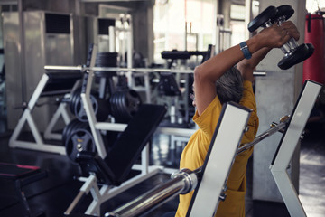 senior man exerise raising dumbbell in gym