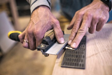 Carpenter sharpening a chisel close up view with focus on fingers