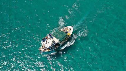 Aerial top view photo of big traditional fishing boat cruising in emerald sea near port of Paros island, Cyclades, Greece