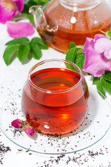 fragrant tea with wild rose in a glass cup on a white background, top view closeup
