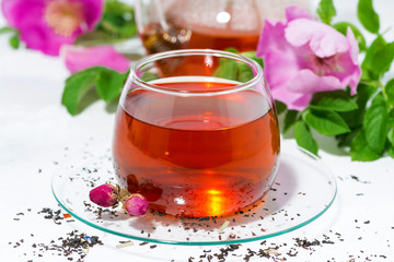 fragrant tea with wild rose in a glass cup on a white table, closeup