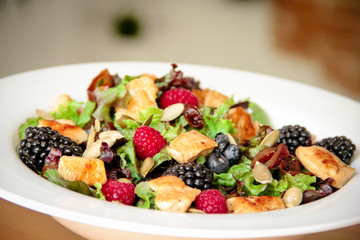 Healthy salad bowl with grilled chicken, caramelized onion and berries.