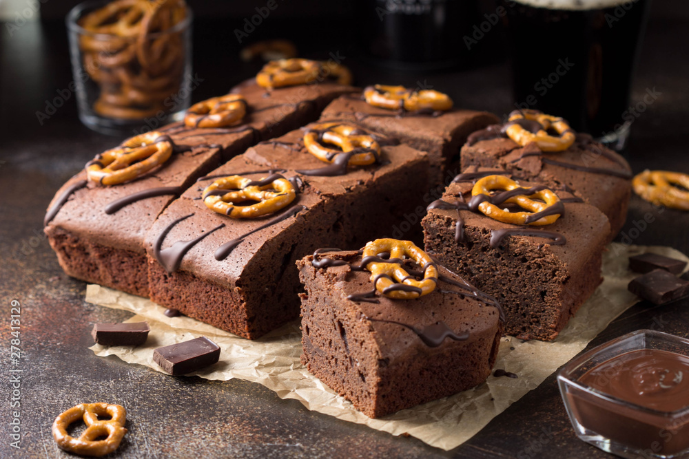 Wall mural Chocolate brownie on dark beer with salted pretzels and chocolate. Delicious brutal dessert for men, sweet food