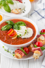 Tomato cold gazpacho soup with vegetables, mozzarella, salami, croutons and basil. Traditional Spanish summer food